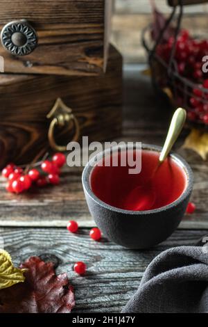 Tee mit Viburnum-Beeren in einer Schüssel, auf einem Holztisch Stockfoto