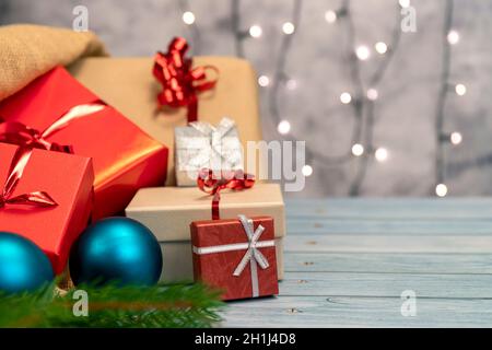 Jute Sack voller Weihnachtsgeschenke. Geschenke mit rotem, braunem und silbernem Papier mit rotem Band, Weihnachtsdekorationen und funkelnden Lichtern in der BA Stockfoto
