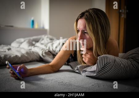 Hübsche Frau mittleren Alters mit Ihrem Tablet-PC vor dem Schlafen im Bett am Abend Stockfoto