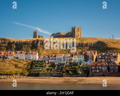 Die Ruinen der St Mary's Church und der Whitby Abbey befinden sich auf der East Cliff oberhalb der Cottages der Henrietta Street, mit dem Strand und dem Hafen von Tate Hill im Vordergrund. Whitby. Stockfoto