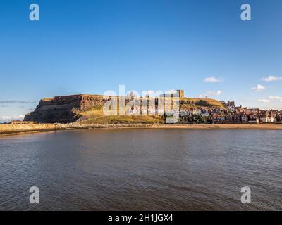 Die Ruinen der St Mary's Church und der Whitby Abbey befinden sich auf der East Cliff oberhalb der Cottages der Henrietta Street mit dem Hafen im Vordergrund. Whitby, North Yorkshire, Großbritannien Stockfoto