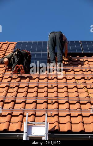 Ochojno, Polen - 8. April 2020: Arbeiter installieren Solarmodule auf einem Hausdach in Ochojno. Polen Stockfoto