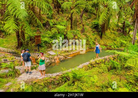 Sao Miguel, Azoren, Portugal, 16. August 2020: Touristen beobachten den Dampf von heißen Quellen und Fumarolen am Rande von Caldeira Velha Stockfoto