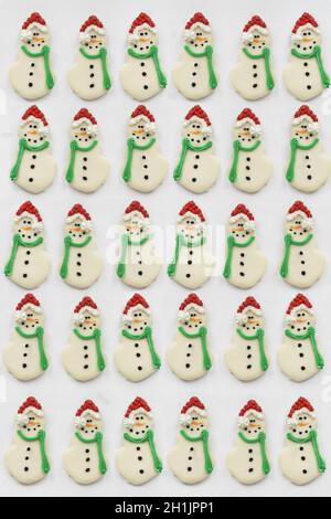 Eisgekühlte Weihnachts-Schneemann-Kekse oder Kekse mit Karottennase, Weihnachtsmütze und Schal. Schneemänner aus flacher Lage oder Draufsicht Position geschossen. Stockfoto