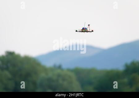 Kleine selbstgemachte FPV Racing Quad Copter Kamera Drohne fliegt vor den malvern Hügeln und Bäumen. Selektiver Fokus auf dieses autonome Flugzeug Stockfoto