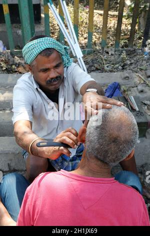 Straße Friseur rasieren ein Mann mit einem Rasiermesser auf einer Straße in Kolkata, West Bengal, Indien blade Stockfoto