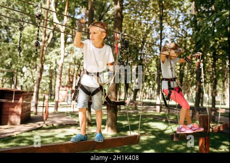 Kleine Mädchen und Junge klettert im Seilpark. Kinder klettern auf Hängebrücke, Extremsportabenteuer im Urlaub, Gefahr Unterhaltung im Freien Stockfoto