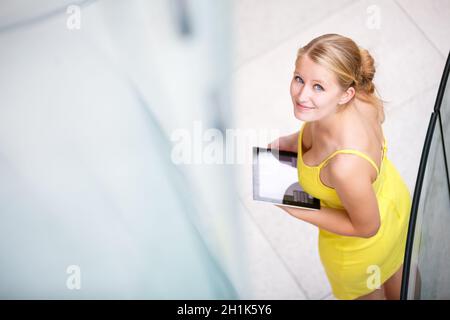 Hübsche, junge Frau mit einem Tablet-Computer im Unternehmenskontext Stockfoto