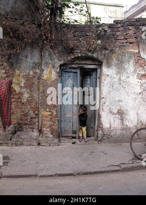 Straßen von Kalkutta. Junge, der in der Tür stand und die Straße hinunter schaute. Stockfoto