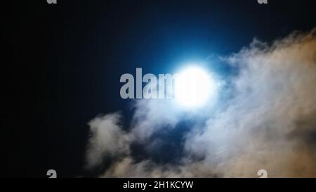 Blauer Mond scheint durch Nachtwolken Stockfoto