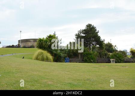 Grashang mit Sitzgelegenheiten, Sträuchern und Bäumen vor der historischen Festung Redoubt auf der Royal Parade in Eastbourne Stockfoto