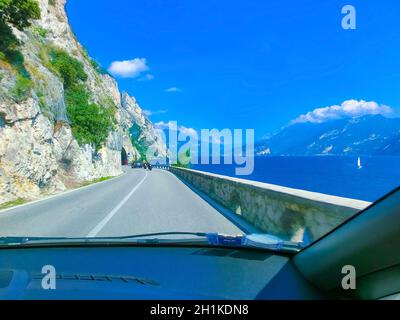 Limone sul Garda, Italien - 21. September 2014: Hohe Berge und Straße am Ufer, Gardasee, Italien, Europa. Blick durch die Windschutzscheibe des Autos Stockfoto