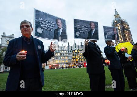 London, Großbritannien. Oktober 2021. Anhänger des Nationalrats des Widerstands des Iran (NCRI) halten Bilder und Kerzen vor einer Gedenkstätte für Sir David Amess, der letzte Woche mehrmals bei einer Wahlkreisoperation in Leigh on Sea getötet wurde, Essex.Anglo-iranische Gemeindemitglieder hielten eine Gedenkfeier und Mahnwache vor dem Parlament ab, um dem ermordeten Abgeordneten Sir David Amess zu Tribut zu zollen. (Foto von Tejas Sandhu/SOPA Images/Sipa USA) Quelle: SIPA USA/Alamy Live News Stockfoto