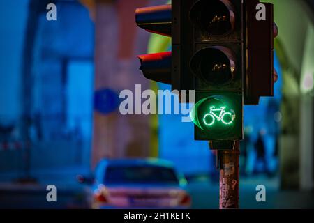 Ampel in München, Bayern, Deutschland. Grüne Fahrrad-Symbol mit Nacht Straße im Hintergrund. Reisen und Transport in Europa.