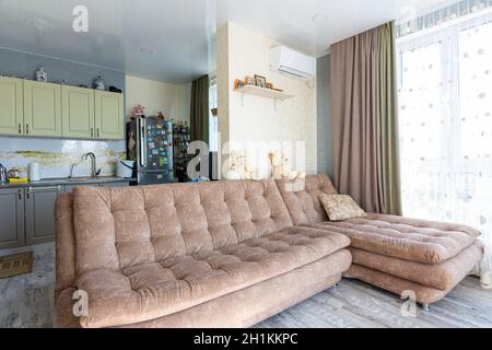 Anapa, Russland - 23. August 2020: Geräumiges Wohnzimmer mit großem Sofa und Küche im Hintergrund Stockfoto