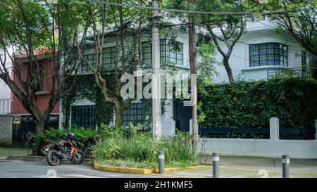 Bild eines großen weißen Hauses aus dem Viertel Coyoacan mit einem Motorrad, das draußen geparkt ist Stockfoto