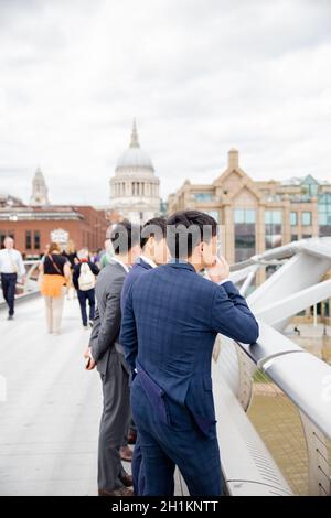 London, Großbritannien - 4. Januar 2019: Porträtansicht von jungen Männern in Geschäftskleidung, die den Blick von der Millenium Bridge und der St. Pauls Cathedra bewundern Stockfoto