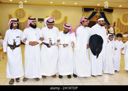 2020. Juli, Hochzeitssaal Riad, Saudi-Arabien, Saudi-arabische Männer feiern und genießen traditionellen Tanz mit kulturellen Objekten in den Händen während der Hochzeit Veranstaltung Stockfoto