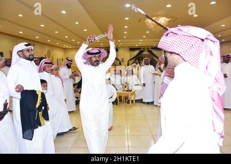 2020. Juli, Hochzeitssaal Riad, Saudi-Arabien, Saudi-arabische Männer feiern und genießen traditionellen Tanz mit kulturellen Objekten in den Händen während der Hochzeit Veranstaltung Stockfoto