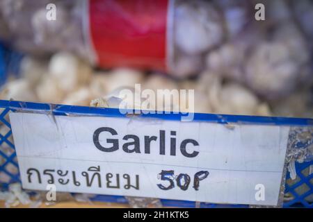 Bild des Wortes Knoblauch in Thai geschrieben auf Zeichen auf einem blauen Plastikkorb voller Knoblauch Stockfoto