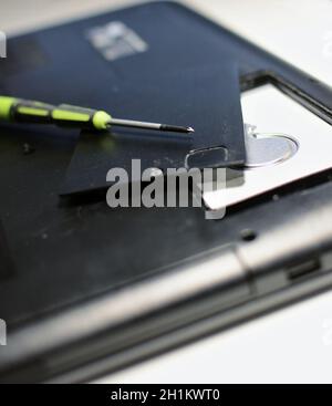 Nahaufnahme des Schraubendrehers und der Festplatte während der Reparatur des alten Laptops. Stockfoto