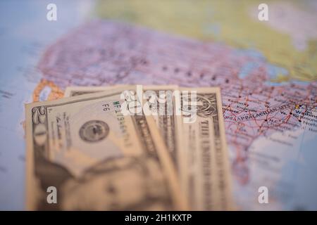 Nahaufnahme von verschwommenen Banknoten von einem, zwei und zwanzig Dollar unter einer violetten Karte der Vereinigten Staaten von Amerika mit ihren Hauptrouten Stockfoto