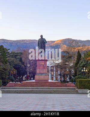 Lenin-Denkmal in Jalta bei Sonnenuntergang, Grünfläche und Bergblick im Hintergrund, Krim Stockfoto