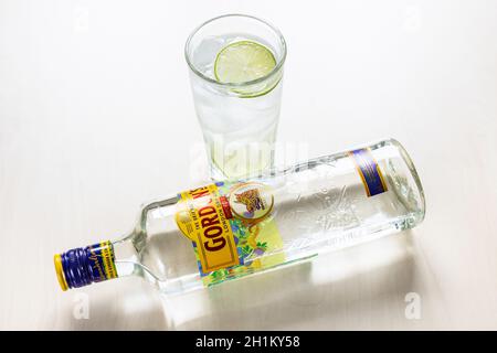 MOSKAU, RUSSLAND - 4. NOVEMBER 2020: Oben liegende Flasche Gordon's London Dry Gin und Gin und Tonic Cocktail im Highballglas auf hellbraunem B Stockfoto