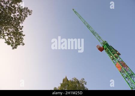 Glatter Himmel am frühen Morgen Hintergrund hinter den Blättern von Baumkronen und der führende Jib eines großen Turmkran. Abstrakt mit viel Platz für Kopien. Stockfoto