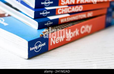 Rom, Italien, 15. November 2020: Das Lonely Planet-Logo auf der Rückseite einer Reihe gestapelter Reiseführer. Berühmte australische Marke von Reiseführern. Stockfoto