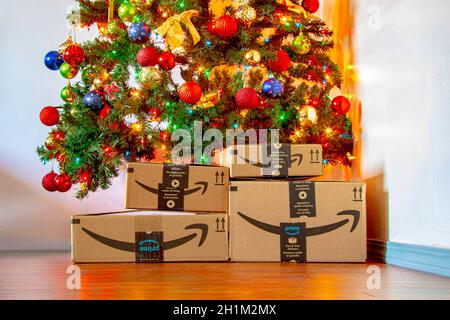 Calgary, Alberta, Kanada. November 16, 2020. Amazon-Boxen unter einem Weihnachtsbaum mit Ornamenten und Leuchten an. Konzept: Einkaufen während der Ferien. Stockfoto