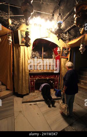 Frauen beten an dem silbernen Stern, der den traditionellen Ort der Geburt Jesu in einer Grotte unterhalb der Geburtskirche von Bethlehem, Bethlehem, Israel, darstellt Stockfoto