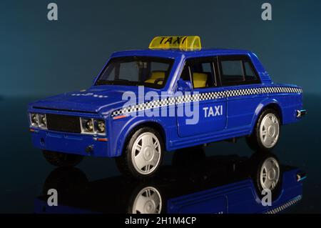 Eine ganze Vorderansicht eines blauen Taxi-Modellautos auf blauem Hintergrund. Stockfoto