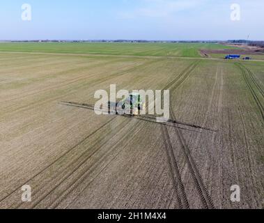 Traktor mit aufklappbaren Sprühen von Pestiziden. Düngung mit einem Traktor, in Form eines Aerosols auf dem Gebiet der Winterweizen Stockfoto