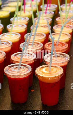 Nahaufnahme viele Plastikgläser mit frischem Obst und Gemüsesäften und Smoothies mit Trinkhalmen im Einzelhandel, Blick aus der Höhe Stockfoto