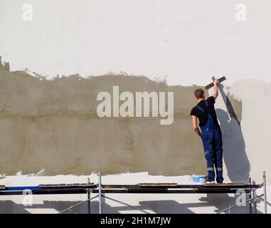 Slavjansk-na-Kubani, Russland - 9. September 2016: gipser Bauarbeiter verputzte Wand in einem kommerziellen Gebäude. Arbeiten auf Gerüsten. Stockfoto