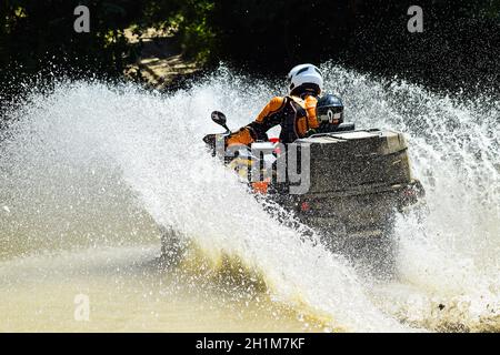 Der Mann auf dem ATV kreuzt einen Stream. Touristischen Spaziergänge auf einem cross-country Gelände. Stockfoto