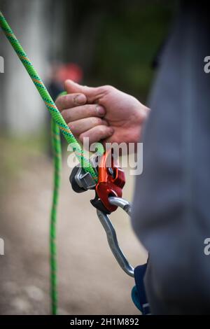 Nahaufnahme der Hände eines Mannes, der eine Klettervorrichtung bediente. Stockfoto