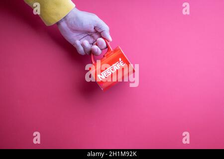 Kuala Lumpur, Malaysia - 12. November 2020 : Hand haltenden Nescafe Becher auf rotem Hintergrund Stockfoto