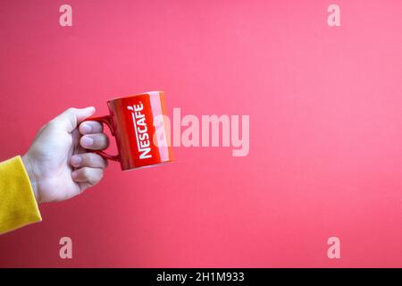 Kuala Lumpur, Malaysia - 12. November 2020 : Hand haltenden Nescafe Becher auf rotem Hintergrund Stockfoto