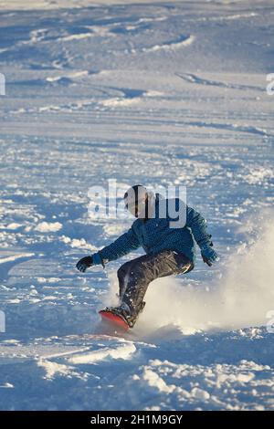 LES ORRES, FRANKREICH - UM 2015: Junge Snowboarder kommen im frischen Pulverschnee abseits der Piste schnell runter. Stockfoto