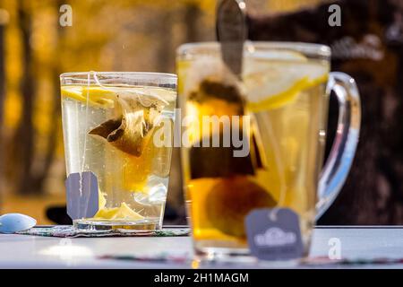 Durchsichtiger Becher mit Tee. Tee in einer Tüte zubereiten. Tee mit Zitrone. Stockfoto