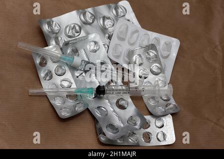 Stapel von gebrauchten leeren Silberblasen Pillen und Spritzen mit Nadeln Stockfoto