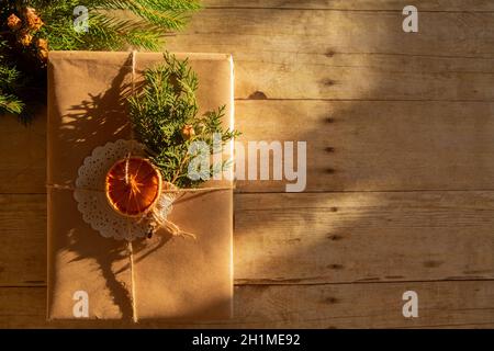 Weihnachtsgeschenk in Vintage-Bastelpapier verpackt. Dekoriert mit getrockneten Orangen und Thuja-Zweig-Flatlay Stockfoto