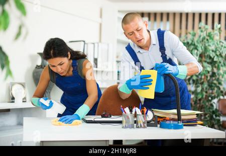 Professionelle Mitarbeiter von Reinigungsservice wischen Möbel im Büro Stockfoto