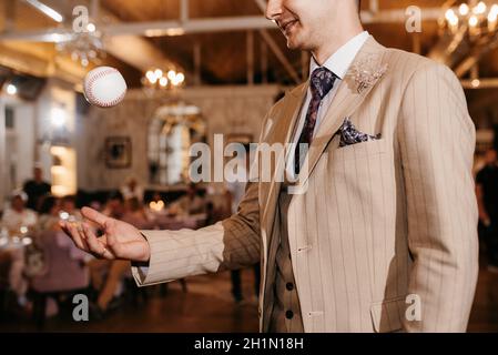 Baseballball mit roten Nähten in der Hand des Mannes Stockfoto