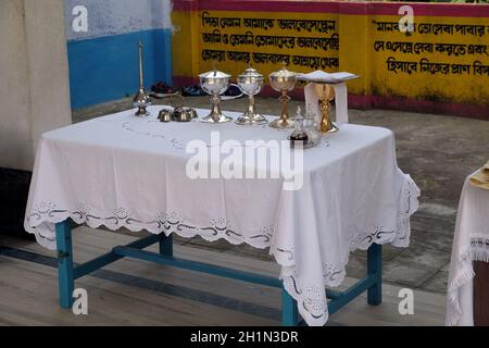 Kelche, die vor der Messe in der Kirche im Dorf Kumrokhali, Westbengalen, Indien, neben dem Altar angeordnet sind Stockfoto