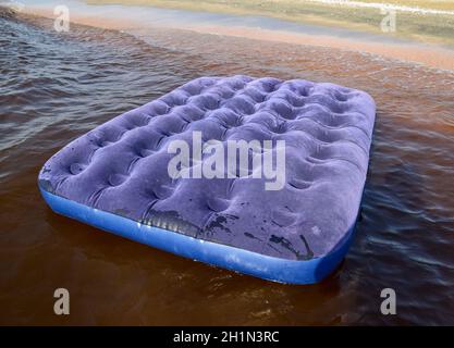 Blaue Luftmatratze im Teich schwimmen. Eine aufblasbare Matratze am Strand. Stockfoto