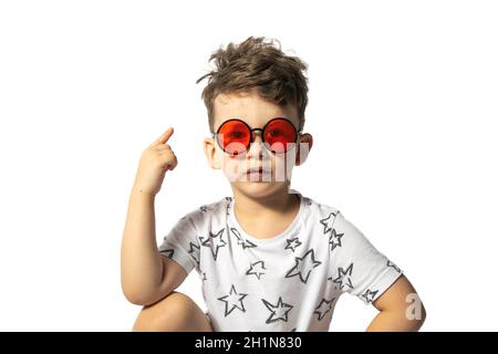 Kleiner kaukasischer Junge in roten Gläsern zeigt die Daumen isoliert auf weißem Hintergrund. Stockfoto
