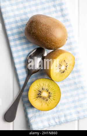 Halbierte reife gelbe Kiwi-Frucht auf karierter Serviette. Draufsicht. Stockfoto